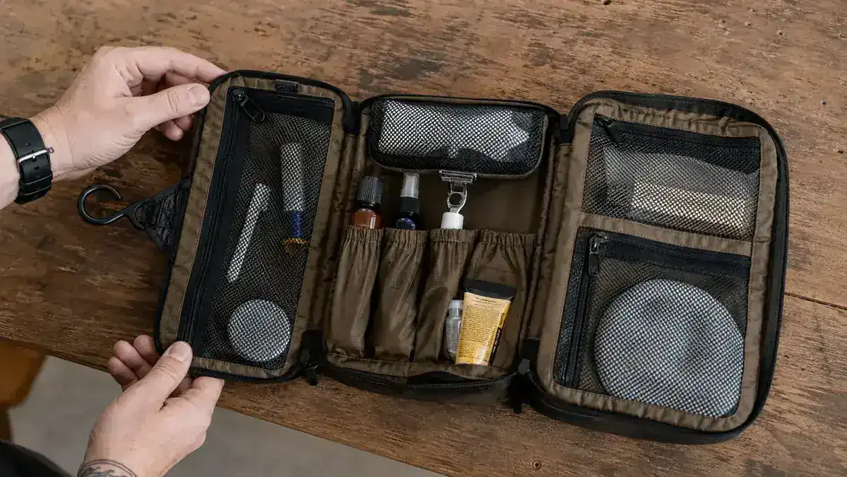 Bottom pocket of a hanging toiletry bag showing water pooling around a travel-size shampoo bottle