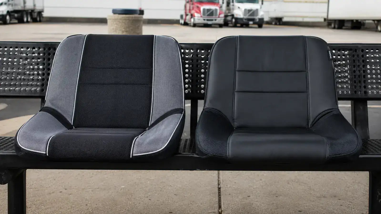 A worn truck cab seat with a dark memory foam cushion placed on the driver's side, highway visible through windshield in morning light
