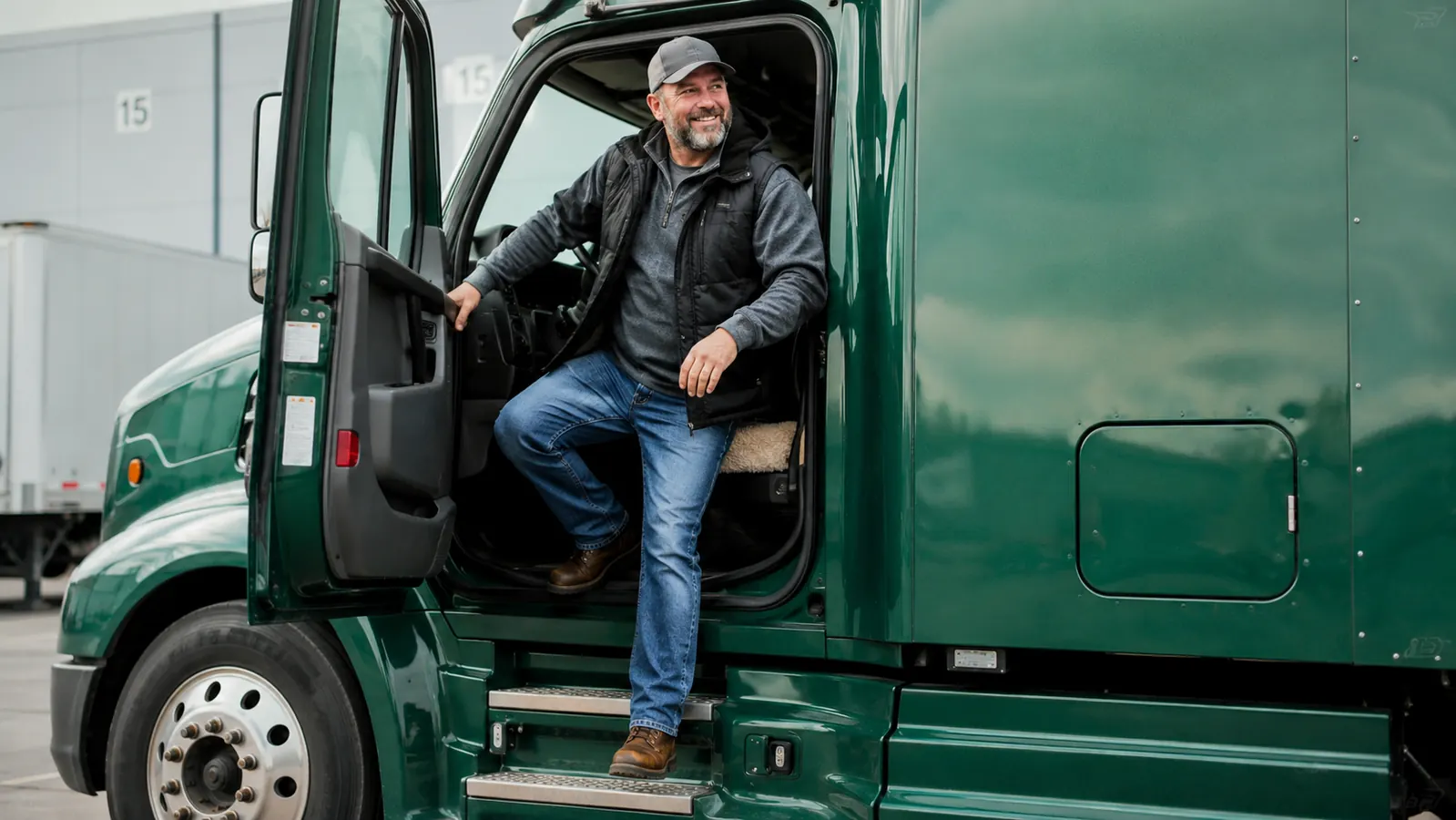 Trucker stretching his lower back at a fuel stop beside his rig, looking relieved